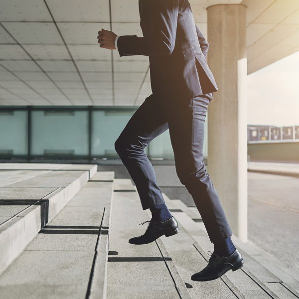 Mann in schwarzem Anzug läuft steinerne Treppenstufen hinauf
